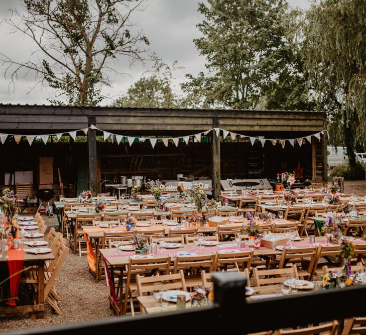 Outdoor farm wedding reception with rainbow wedding decor 