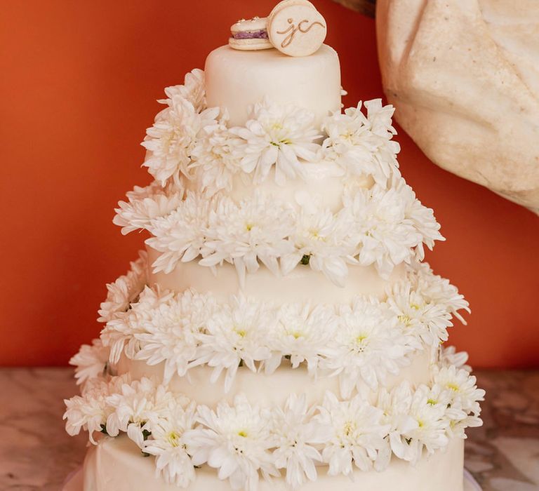 White iced wedding cake with flower decor and macaroon cake toppers 