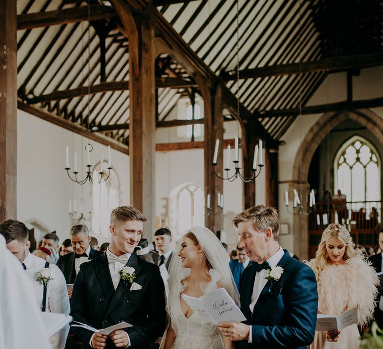 Bride in Inbal Dror wedding dress and groom in navy suit standing at the altar 