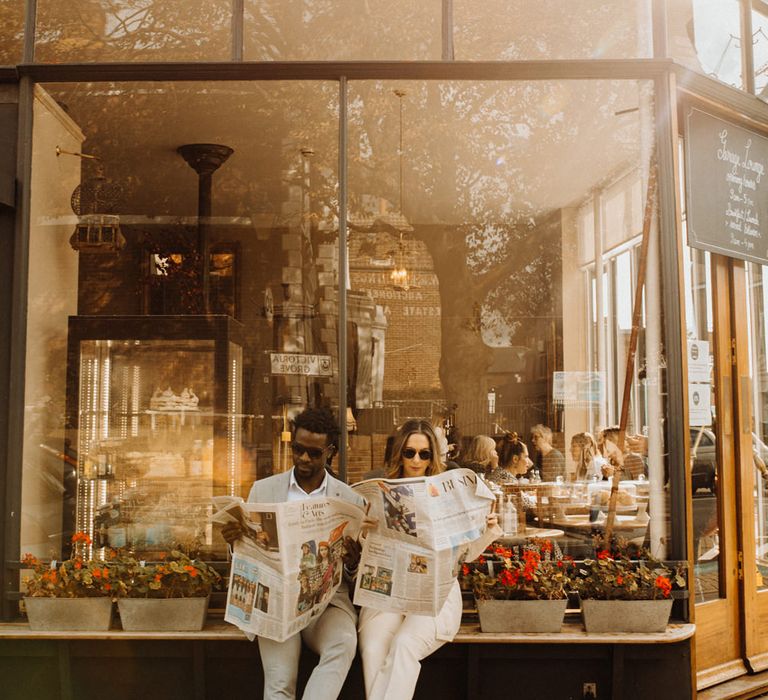 Bride and groom reading newspapers at city elopement 