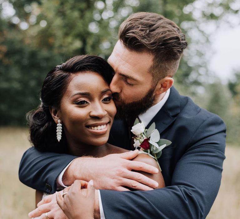 Groom embracing his bride at their autumn wedding 