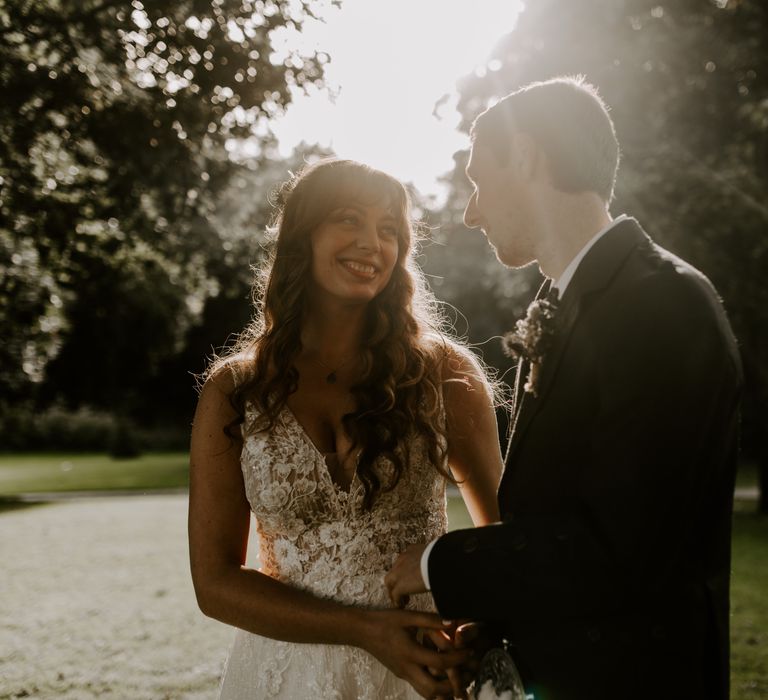 Bride and groom smile and hold hands as the sun shines down on them in Scotland 