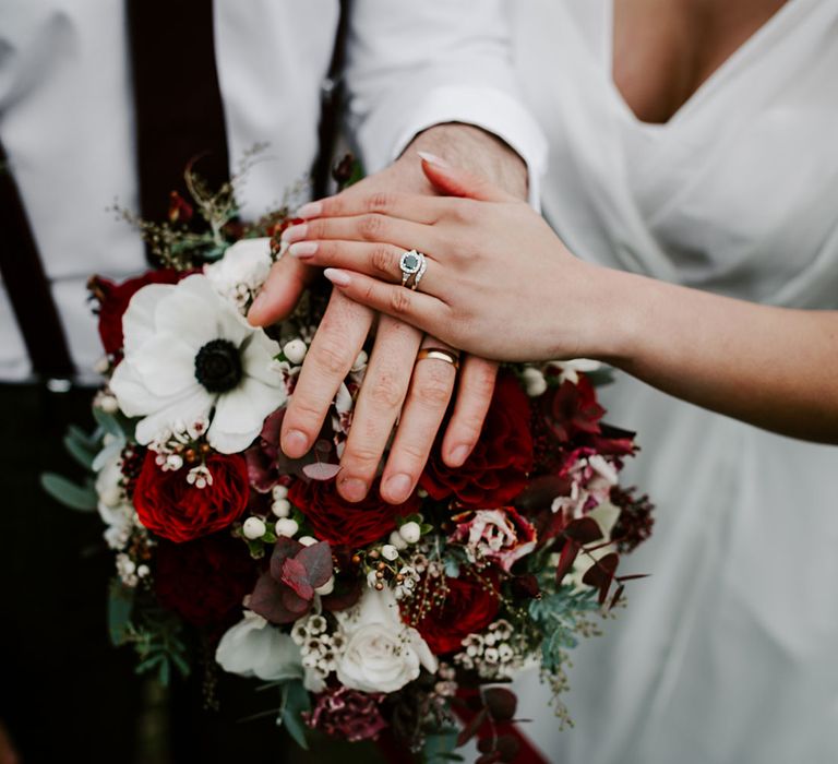 Newly married couple with rings and red and white rose bouquet