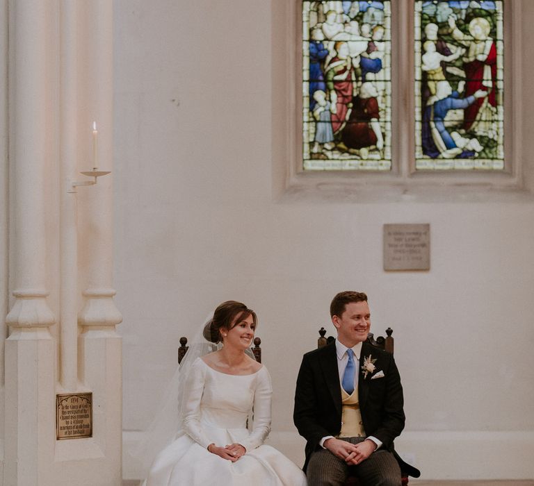 Bride and groom sat in church with stained glass windows