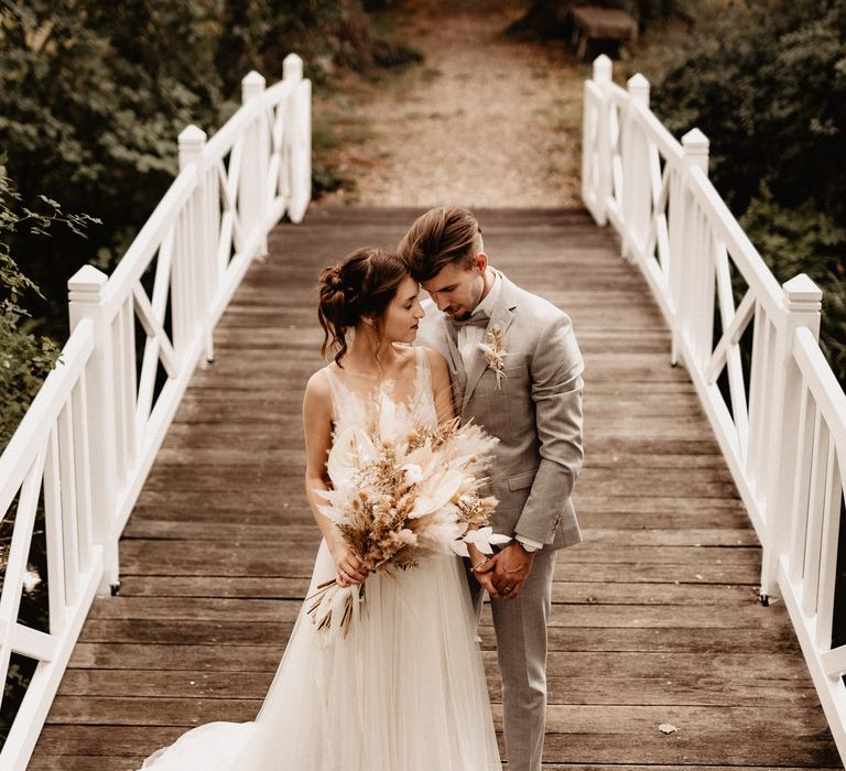 Bride and Groom on a bridge with dried flower wedding bouquet with pampas grass