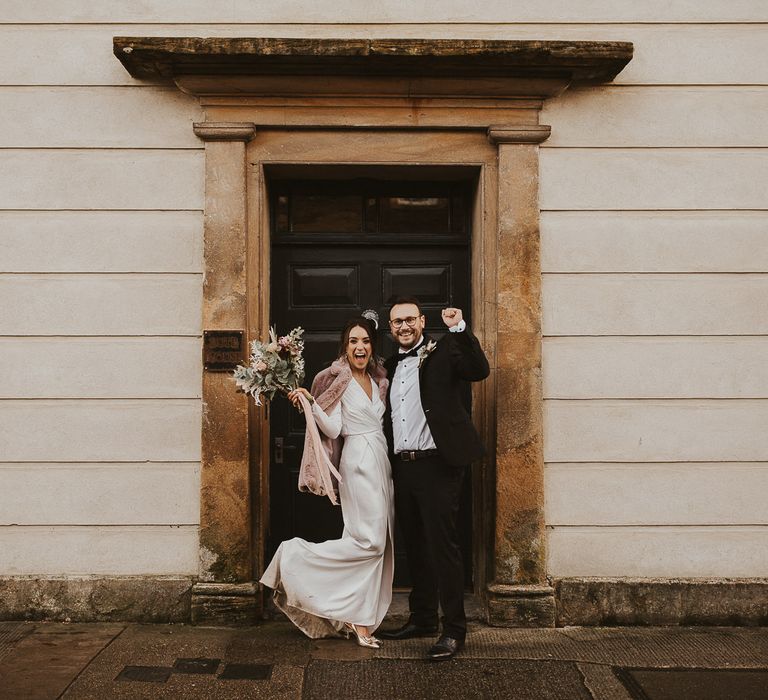 Bride & groom celebrate together with black door backdrop 