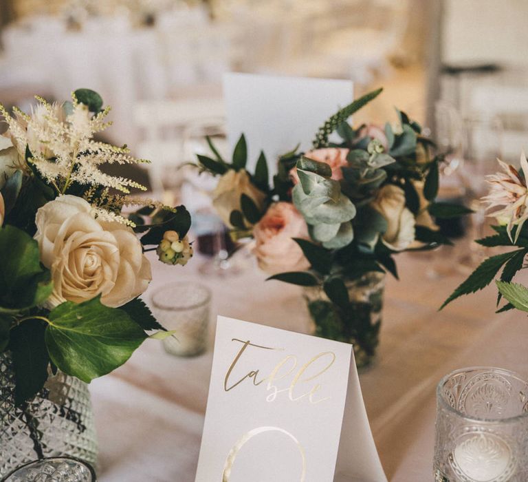 Classic romantic wedding table decorations with roses, candles and gold foil stationery