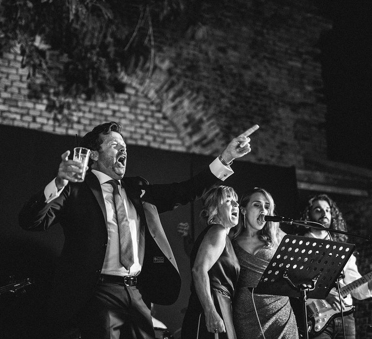 Father of the bride singing with the wedding entertainment at Italian beach wedding reception 