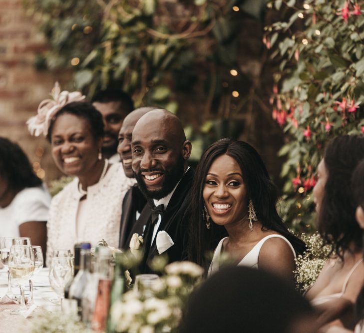 Bride and groom smiling sitting at the top table during the wedding speeches 