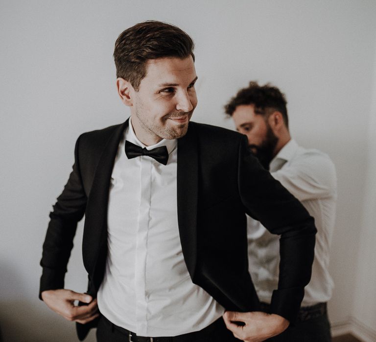 Smiling groom in Tiger of Sweden tuxedo and black silk bow tie