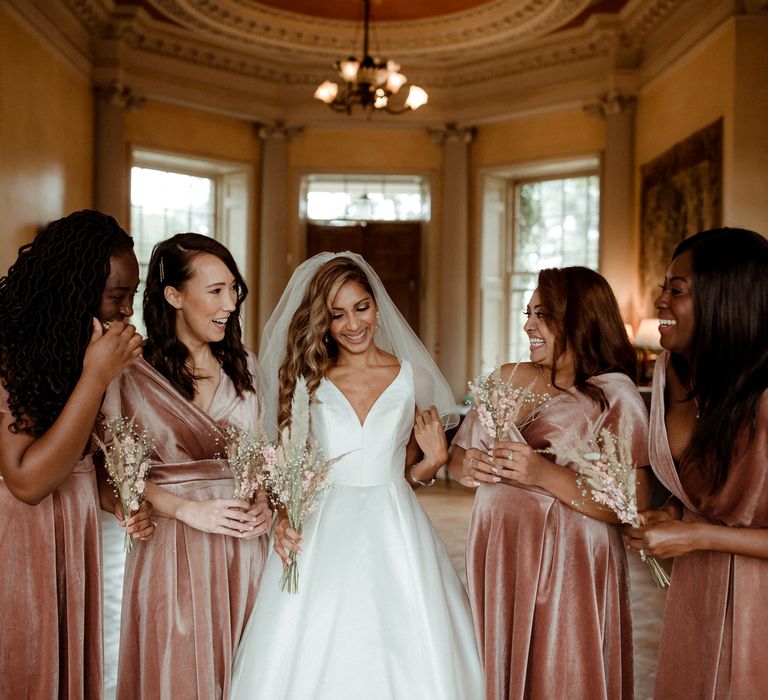 Bride in a taffeta Justin Alexander wedding dress with her bridesmaids in pink velvet dresses at intimate Hampton Court House wedding