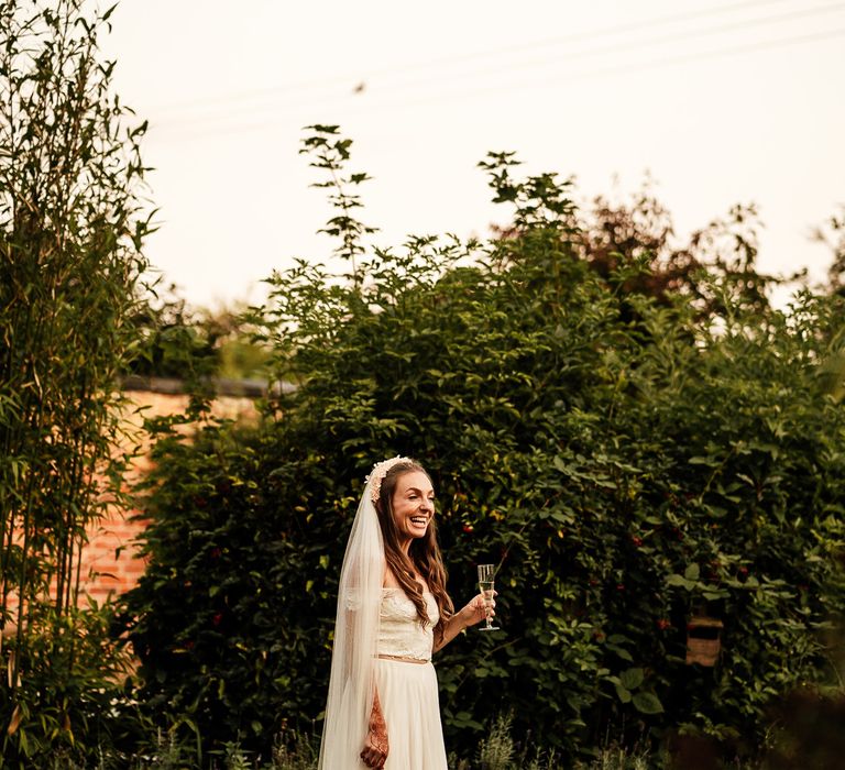 Bride laughs outdoors whilst holding champagne 