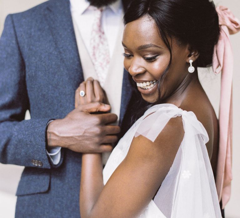 The bride and groom smiling and holding hands, the bride is wearing a one shoulder Anna Campbell dress