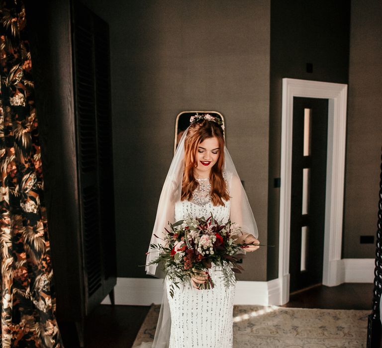 Bride stands holding floral bouquet 