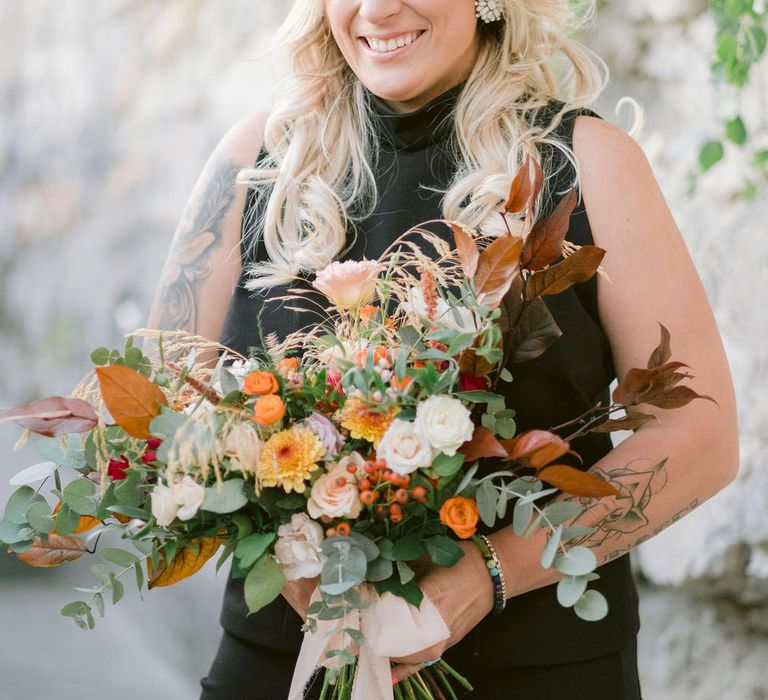 The bride holding her large bouquet of autumnal themed flowers