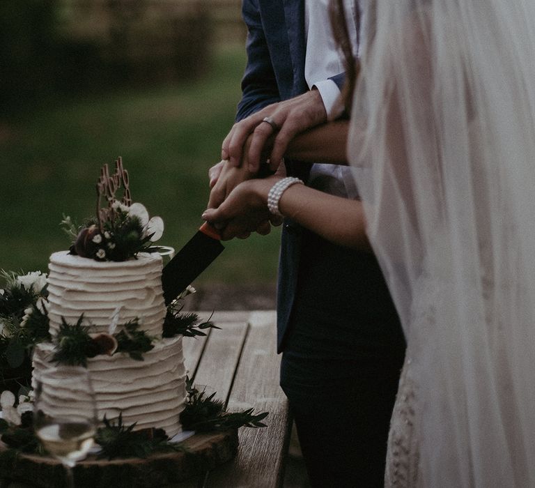 Bride & groom cut cake on their wedding day outdoors