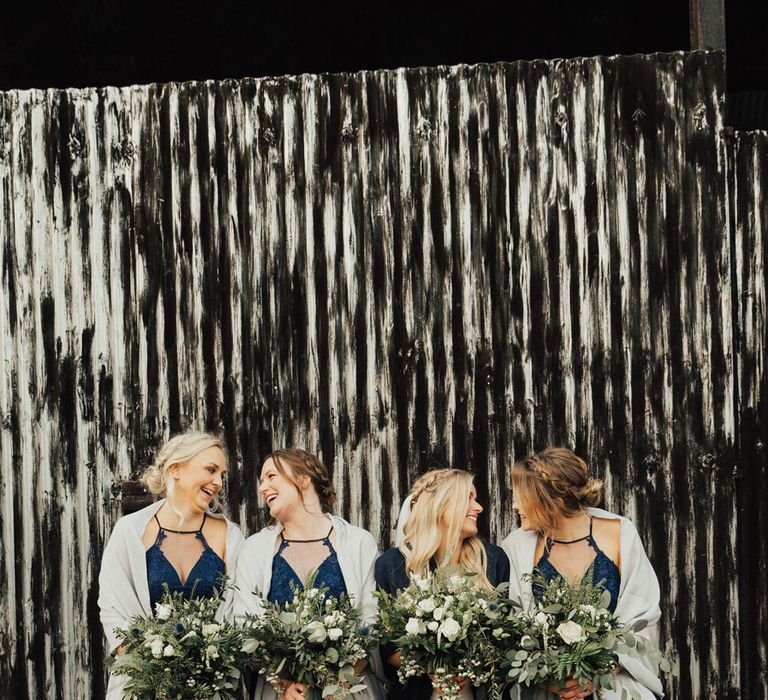 Bridesmaids wearing long chiffon navy blue bridesmaid dresses with mesh and lace halter neck detail, with matching white shawls | Chi Chi Clothing Dresses | Photography by The Wild Bride