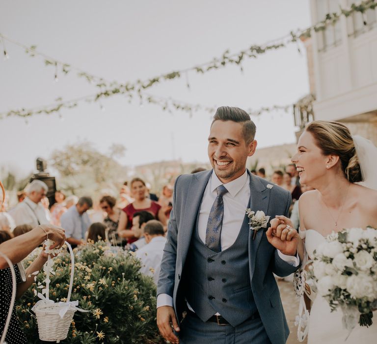 Bride and groom holding hands walking through a crowd of guests at their Turkish Wedding