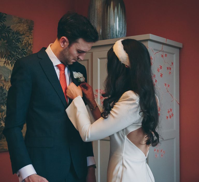 Bride fixing grooms red tie, bride wears short wedding dress and matching headband