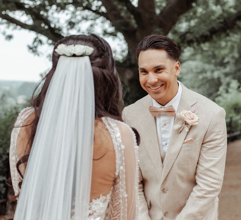 Groom smiles and laughs as he sees his bride for the first time outdoors on their wedding day