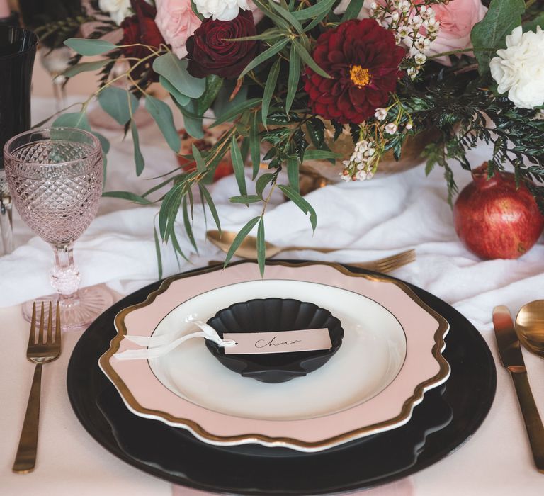 Wedding table decor with black charger plate, pink and gold tableware and floral centrepiece 