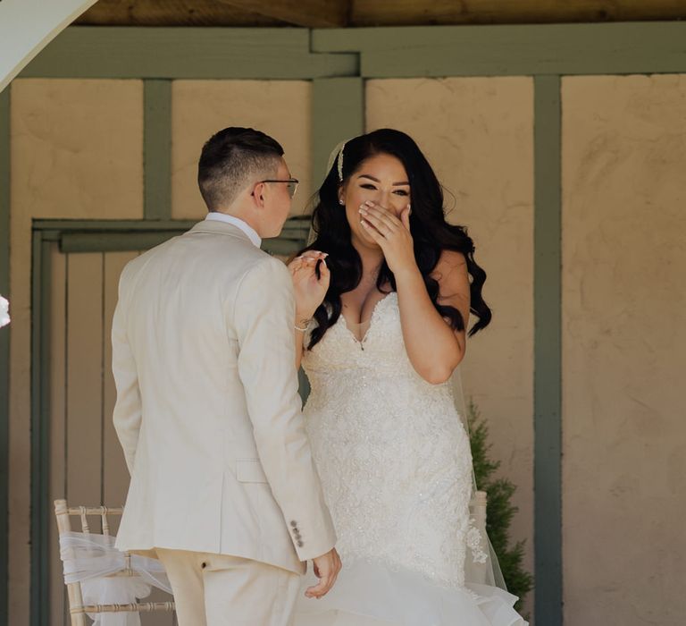 Bride in a strapless fishtail wedding dress laughing during the outdoor wedding ceremony at Cooling Castle Barn 