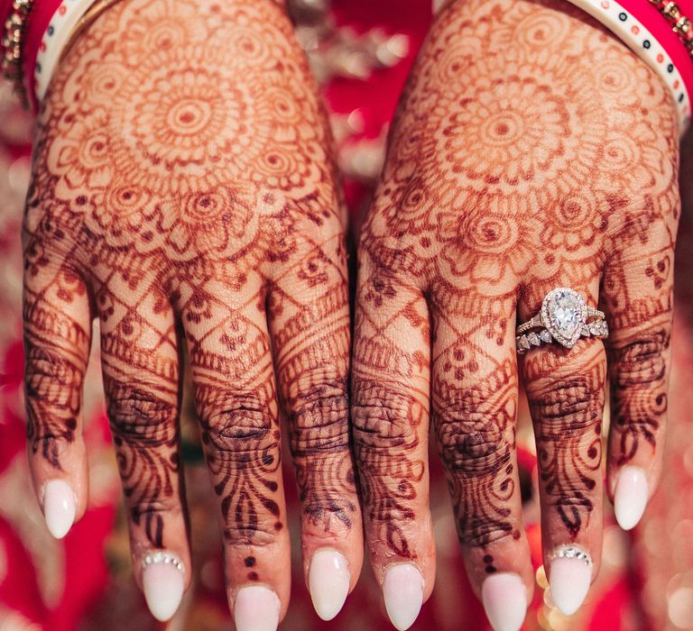 Sikh bride shoes her henna covered hands featuring intricate patterns and wearing a pear shaped diamond wedding ring