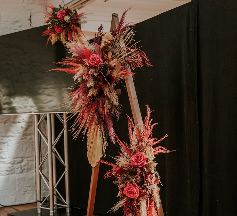 Triangular shaped brightly coloured floral archway for wedding day complete with three disco balls at the bottom and pillar candles