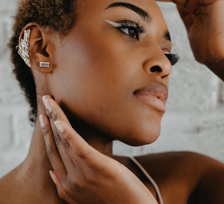 Black bride with short afro hair wearing a silver cuff earring and white winged eyeliner 