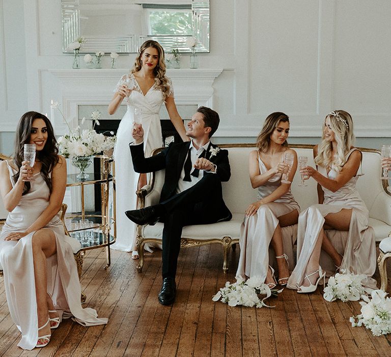 Wedding party sipping champagne at black tie wedding in a tuxedo and Constellation Ame wedding and bridesmaid dresses 