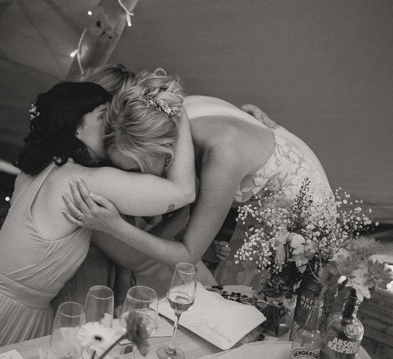 Bride in white Enzoani wedding dress hugs bridesmaids in asos bridesmaid dresses during tipi wedding reception at Inkersall Grange Farm wedding