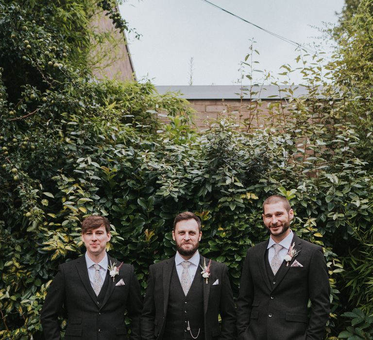 Groomsmen in matching wedding suits with patterned ties and flower buttonhole