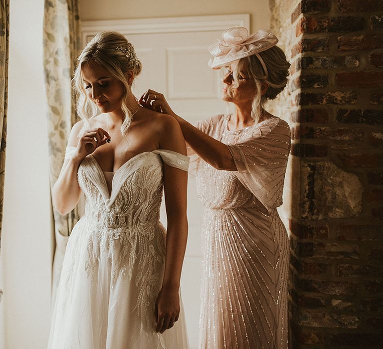 Bride puts on Pronovias lace wedding dress with off the shoulder detail