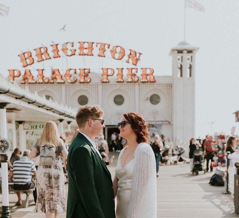 Bride & groom look lovingly at one another in front of Brighton Pier on their wedding day