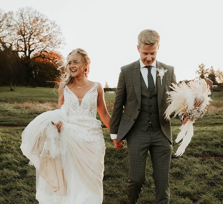 Bride in Eleganzza Sposa wedding dress walks hand in hand with groom