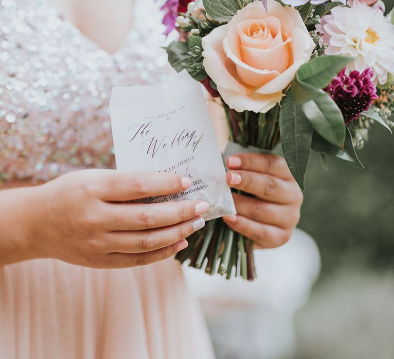 Bridesmaid in blush pink sparkly dress holding special scented confetti and assorted wedding bouquet