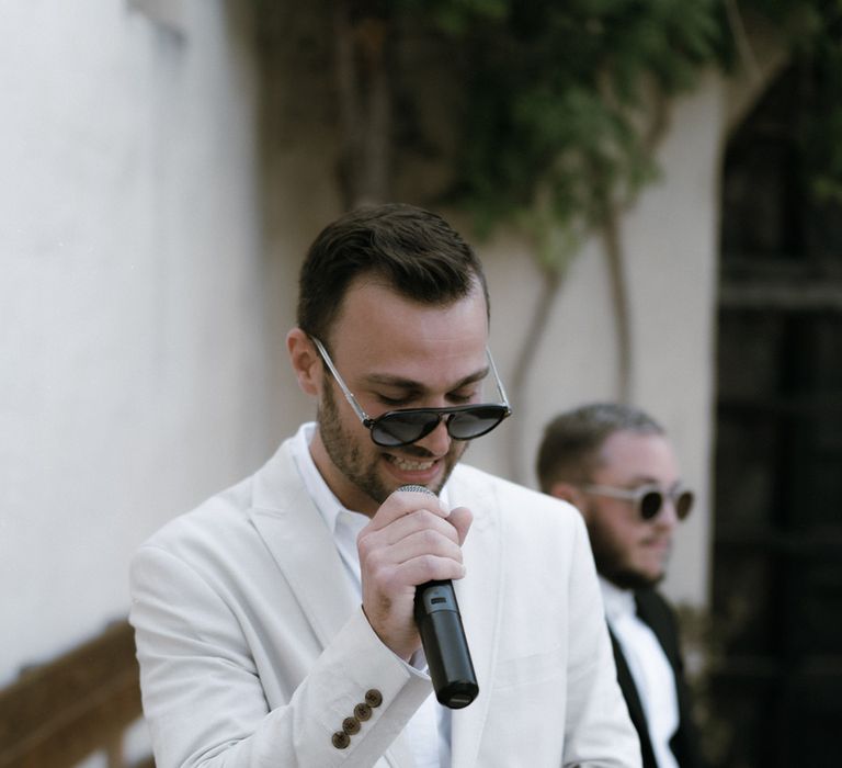 Wedding guest in off-white suit and black sunglasses gives a speech at LGBTQI+ wedding 