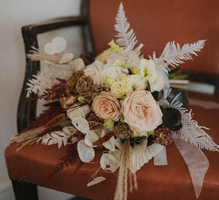 Wedding bouquet with light and dark flowers with roses and dried flowers