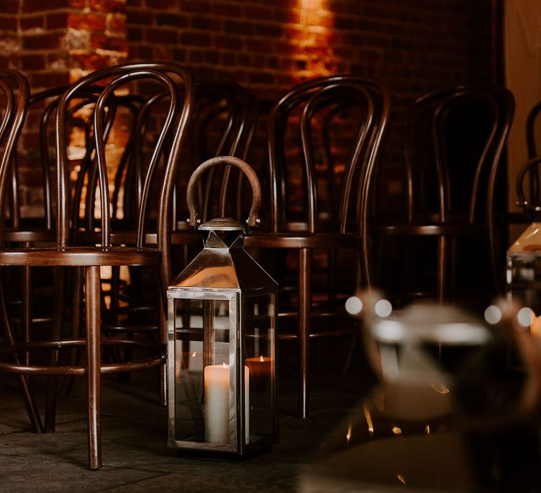 Large silver lanterns with candles inside next to dark wooden chairs for winter wedding