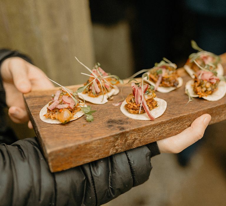 Canapes for guests served on dark wooden board 