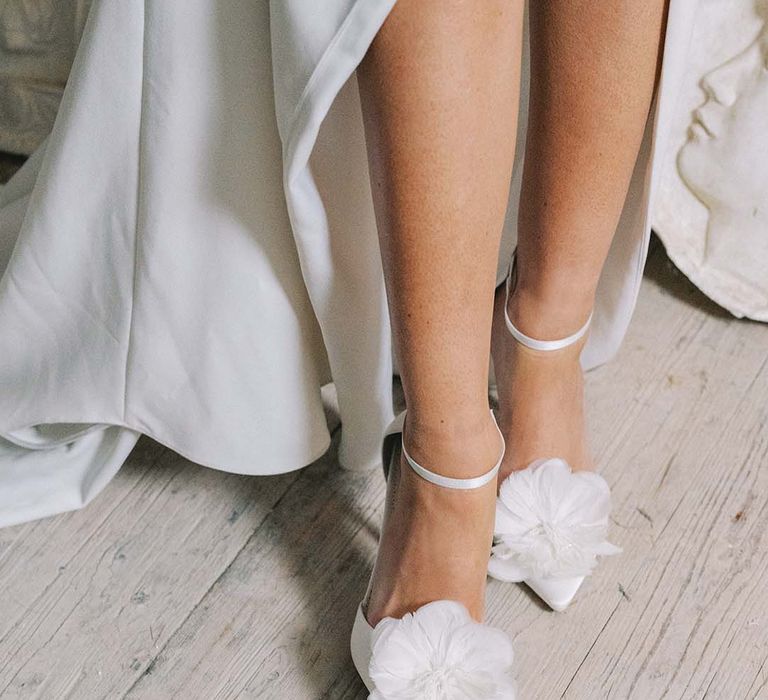 Bride wearing white stiletto wedding shoes with ankle strap and feather flower with beads from Bella Belle 