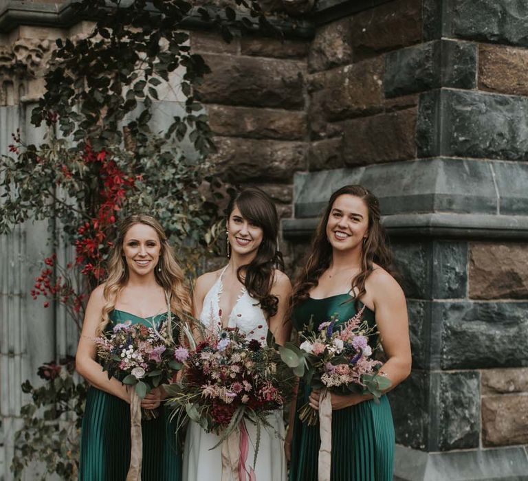 Bridesmaids in emerald green satin bridesmaid dresses with pleats with bride in halter neck lace wedding dress