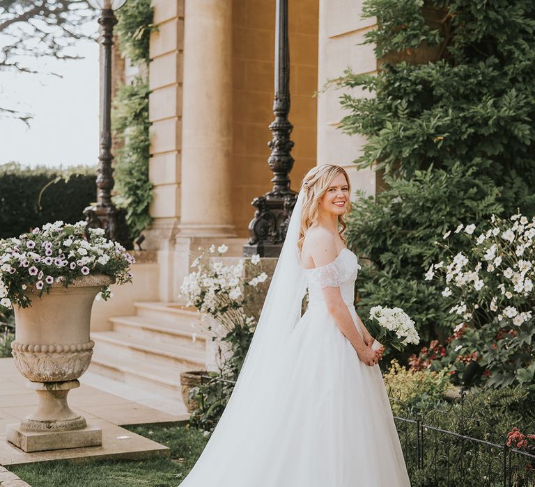 Bride in ballgown wedding dress with off the shoulder wedding dress with white flower bouquet 