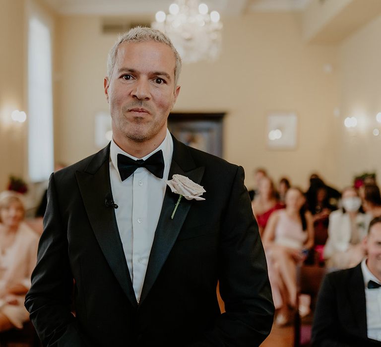 Groom smiles as he waits for the bride to walk down the aisle 