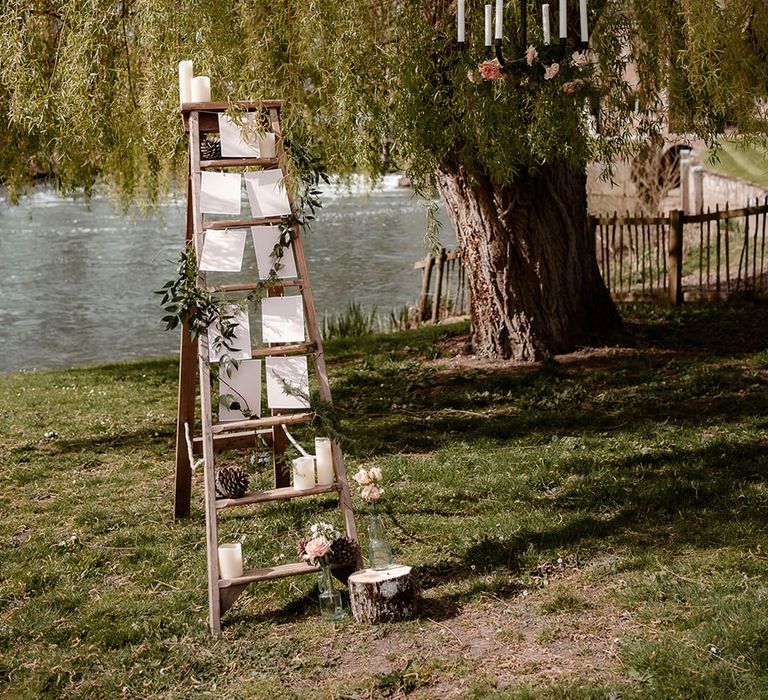 wooden step ladder seating chart idea with hanging chandelier from the tree at Mapledurham 