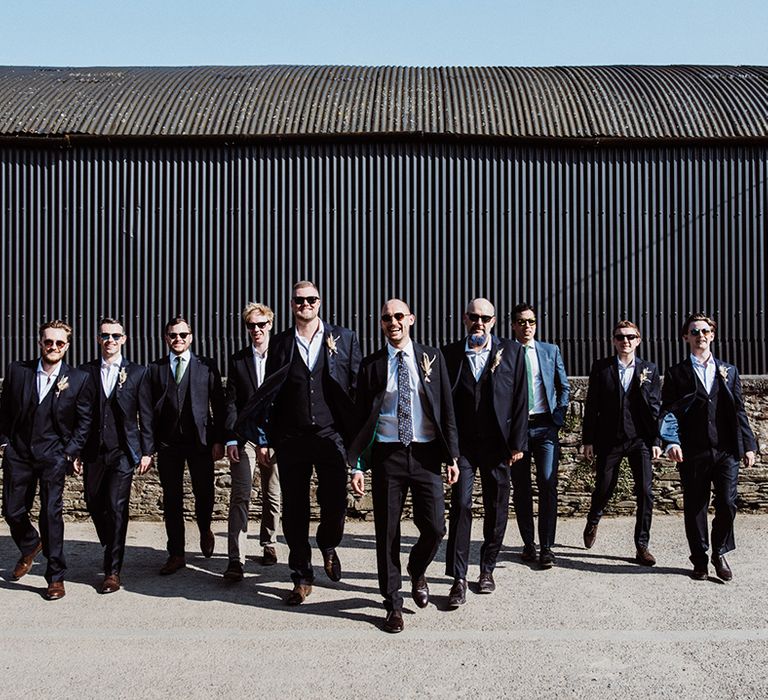 Cool walking groom and groomsmen shot with them all wearing sunglasses 