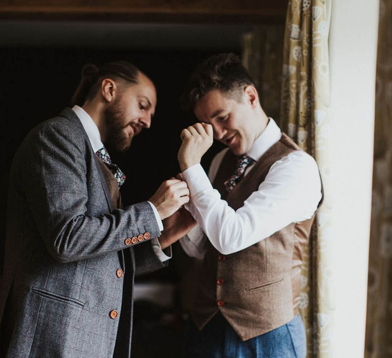 Groomsmen helps the groom put in his cuff links 