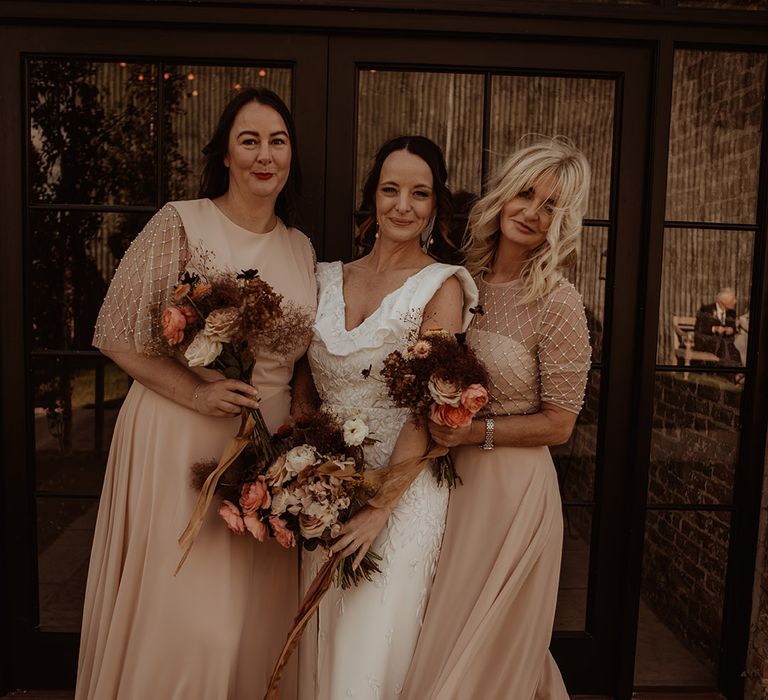 Bridesmaids in blush pink dresses with pearl accents and beading with the bride in a custom Emma Beaumont Atelier wedding dress