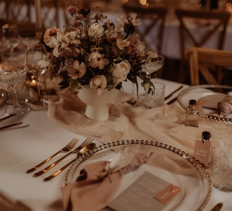 Grey and pink stationery, pink napkins, pink table runner, gold cutlery, gold charger plates, gin wedding favours and soft lighting 