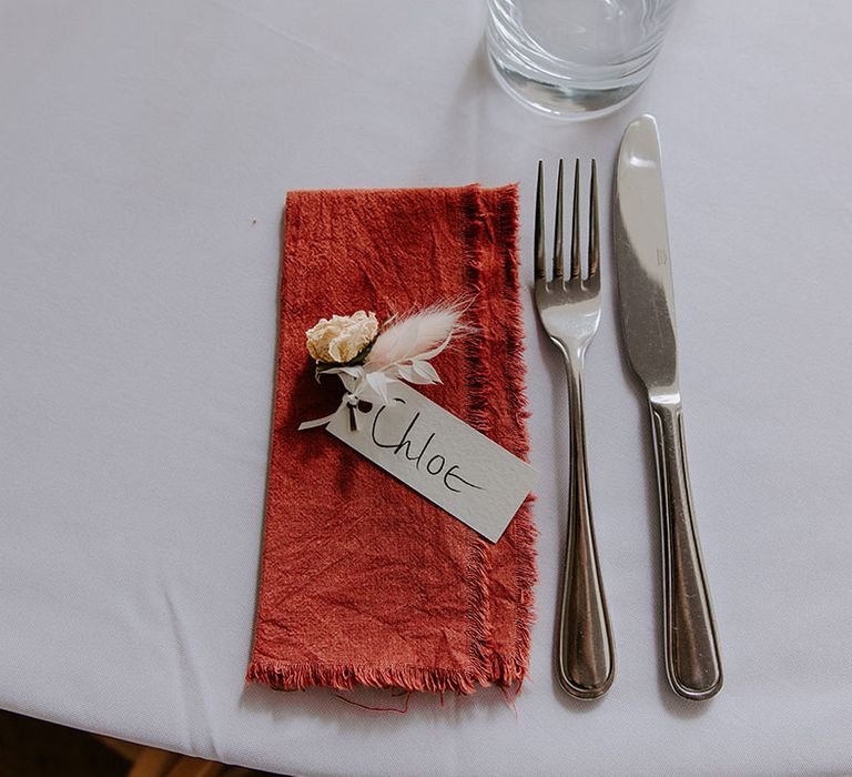 Fabric napkin with frayed edges complete with small floral decor and place name